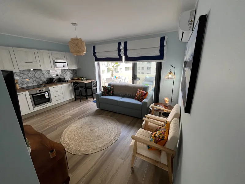 Open-plan living room and kitchen with a sofa, armchairs and doors onto the terrace