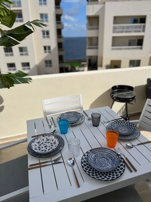 Front terrace dining table laid for four, with a view of the sea between the buildings of Tigné