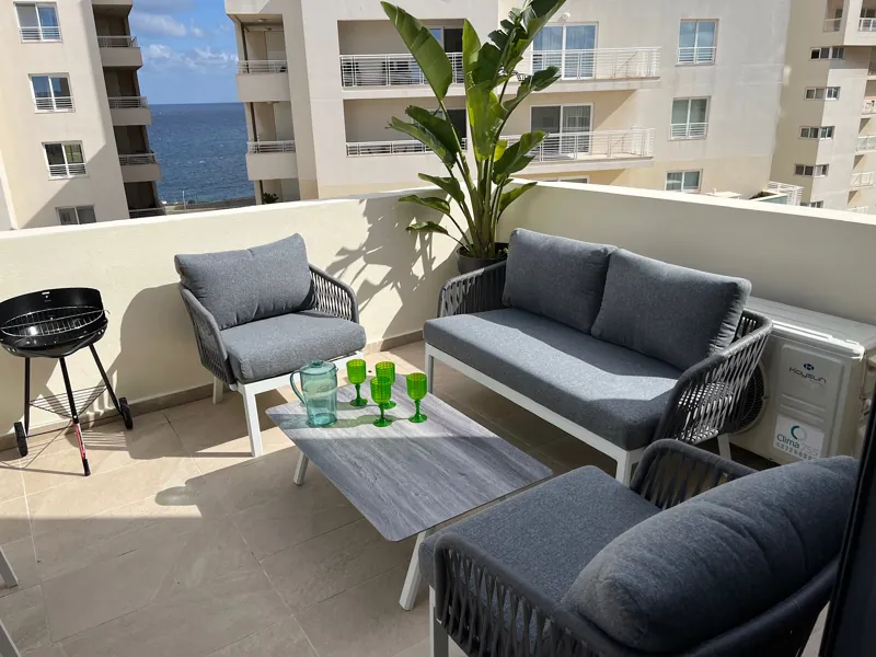 Front terrace lounge with sofa, armchairs and barbecue, looking out to the sea